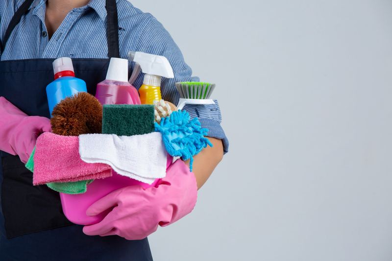 Cleaner holding a bucket of cleaning products